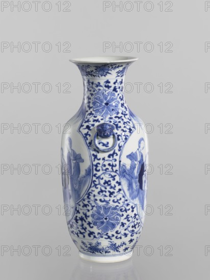 Vase, Chinese, Qing dynasty Kangxi period, 1662–1722. Ovoid blue-and-white porcelain vase with a flaring cup-shaped mouth; height 25.5 cm, diameter 11.1 cm. Shoulders bear two applied mascarons with wheel motifs. Underglaze cobalt decoration includes figural scenes in two quatrefoil reserves and a background of plant ornament with small leaves, large floral rosettes, lotus tendril ornament, fans, and lotuses. Signed., A tall porcelain vase with a flared rim sits against a plain light gray background, decorated in blue on white with intricate floral and scrolling patterns; the body shows oval panels containing figures in traditional dress, and there are stylized floral medallions and vine-like motifs covering much of the surface; a small sculpted ring handle set in a mask-like mount appears on the neck; visible colors include white, several shades of blue, and the neutral gray of the background.