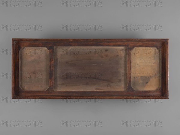 Tray with three rectangular plaques. Porcelain covered with celadon glaze. Chinese; celadons, ceramics, trays; dragons iconography. 19th century. Vessel; height 20.5 cm, width 53.6 cm. Creator, provenance unknown. In a single wooden frame., A rectangular wooden tray with a dark brown frame containing a central recessed panel flanked by two narrower recessed panels, each panel showing worn, uneven surfaces and variations in brown, tan, and beige tones; the frame displays reddish-brown highlights and darker brown grain, and the background is a uniform gray.