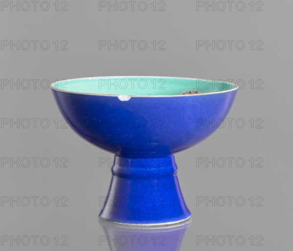 A tall footed porcelain bowl, Chinese, glazed ceramics; outer glaze stained cobalt, inner glaze green; overglaze iron hieroglyphs, overglaze enamel paints, gilding with a gilded edge. 19th century Qing Dynasty. Vessel; height 11.8 cm, diameter 16.8 cm. Maker, provenance unknown. Classification: footed bowl, decorative vessel, colored porcelain., A pedestal bowl photographed against a plain gray background, the exterior glazed in a deep blue and the interior glazed in a pale turquoise, with a thin rim showing a slightly lighter edge; the bowl sits on a tapered foot of the same deep blue and shows small areas of wear on the rim and minor surface scratches.