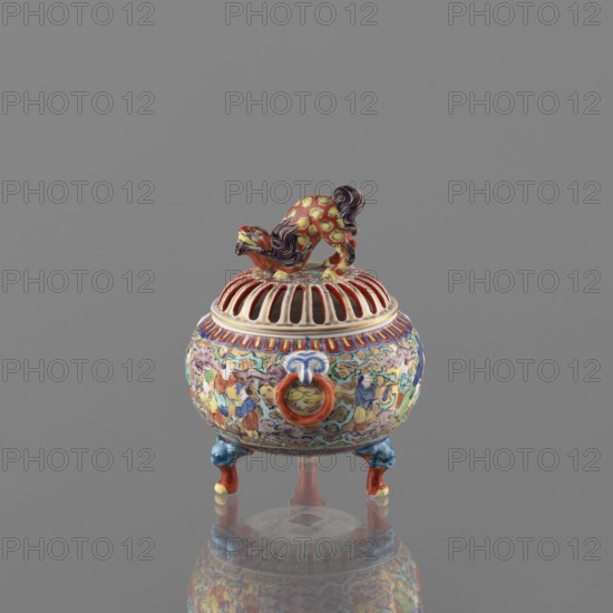 Incense burner with lid, Kutani, figurative scenes, Japanese art, Japanese culture, three-legged vessel, colored porcelain, Meiji 1868–1912, deer, porcelain pottery, grayish white glaze with a bluish tint; overglaze decoration in green, purple, red, blue, yellow with black outlines; 19th/20th century Meiji period, Japan, Kaga province; vessel, incense burner; height 12 cm, diameter 9 cm., A small ornate ceramic censer with a rounded body and a domed, slotted lid topped by a stylized animal figure; the object displays a mix of colors including red, yellow, blue, green, white, orange, purple, and black. The lid has vertical open slats painted in red and white beneath the animal finial, which is patterned with yellow spots and purple mane details. The body is richly painted with a continuous scene of human figures and cloud-like motifs rendered in blue, green, yellow, orange, purple, and white, and it has a circular ring handle accentuated in orange on one side. A decorative band of repea...