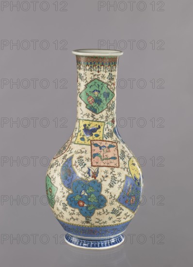 Vase, Japanese, insects and butterflies, colored porcelain with floral decorations and geometric ornaments, cloisonné enamel, Meiji period ca. 1870–1880, Nagoya, Japan; vessel; height 39.5 cm, diameter 20.5 cm;, A tall, bulbous ceramic vase with a narrow neck and flared rim sits against a plain gray background; the vase surface is primarily off-white with decorative panels and floral motifs in a palette of blue, green, yellow, pink, red, and turquoise, accented by dark outlines and small black decorative marks; the neck and body feature a mosaic of shaped panels containing stylized flowers and leaves, with several blue and green floral clusters, a few pink and yellow floral elements, and small butterfly-like shapes; a band of intricate geometric decoration in red, blue, and green encircles the rim and a broad blue decorative band with lighter blue patterning encircles the foot, with delicate vine-like motifs scattered across the off-white ground.