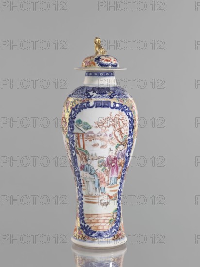 Vase with a lid, Chinese, ceramics, colored porcelain, 18th century. Height 28 cm. Lid topped with a modeled seated lion. Decoration: geometric and plant ornament around the neck; two large reserves bordered with plant ornament filled with figural genre scenes in a landscape, two smaller reserves with figures in a landscape; background of twigs with flowers on a gold ornamental ground. White glaze, underglaze cobalt, overglaze enamels in sepia, black, iron red, and gold. Vessel. Provenance unknown., A tall porcelain vase with a lid sits against a plain gray background, the body showing a glossy white surface decorated with intricate painted scenes framed by ornate blue floral borders; the painted imagery includes a group of people in traditional dress near a landscape with trees, water, and boats, rendered in muted colors such as blue, pink, green, brown, and gold accents; the lid is topped with a small sculpted figure finished in gold, and the rim and base also show decorative blue an...