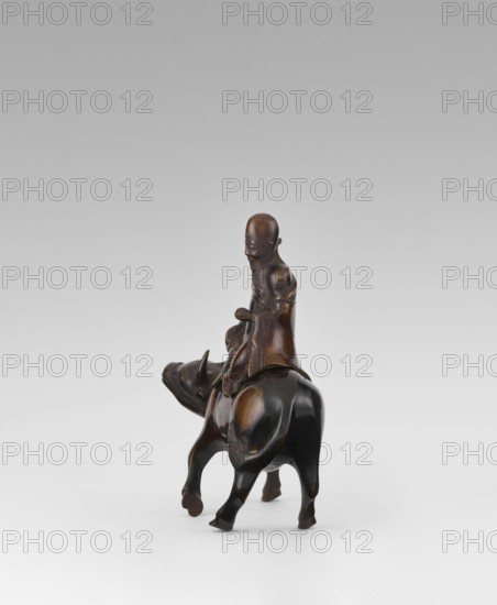 Shoulao on a buffalo - incense burner, Chinese, men, buffaloes, Taoism, incense burner, sage, Shouxing iconography, Qing dynasty 1644–1911, 19th century, China, sculpture/figurine, height 20.7 cm, width 20.7 cm, A dark brown carved figure of a person seated on the back of an animal resembling a water buffalo, both rendered in smooth, polished wood tones with lighter brown highlights on raised areas; the person has a rounded head, elongated facial features, a long beard, and draped clothing that falls over the animal's back, while the animal shows a sturdy body, curved horns, and four legs supporting the figure against a plain light gray to white gradient background.