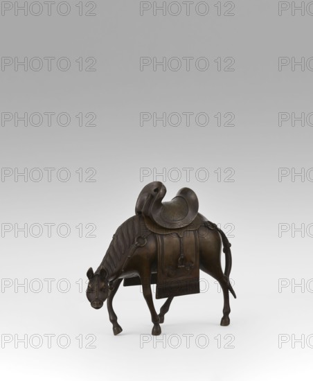 Mule with saddle - incense burner; maker, Qing style; Chinese art; Chinese culture; subject: mule with saddle, saddle cloths; materials/technique: incense burner; date: 19th century Qing, 1644–1911; place of origin: China; height: 16.8 cm., A small bronze sculpture of an animal resembling a horse or mule shown in a three-quarter view, standing on a light surface against a neutral gray background; the figure is rendered in dark brown and bronze tones with a slightly polished patina, featuring a stylized mane with carved ridges, a lowered head with visible ears and muzzle, and four legs with defined hooves; a detailed saddle and saddle cloth rest on its back, the saddle having curved, rounded forms and the cloth hanging down the animal's sides with decorative raised motifs and textured edges; small looped straps and tassel-like elements are attached around the saddle area, and the tail extends downward with a slight curve.