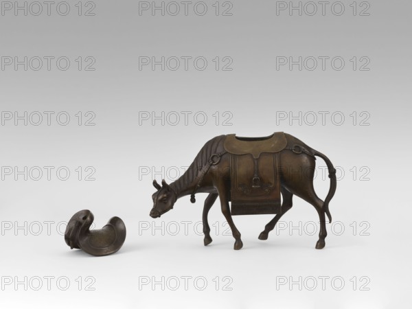 Mule with saddle — incense burner, Qing style, Chinese, 19th century Qing 1644–1911, China; materials/subject: mule with saddle and saddle cloths; height 16.8 cm., A bronze sculpture of a cow with a decorative saddle-like covering on its back stands with its head lowered, showing a detailed mane, ears, and tail; nearby is a separate curved bronze object resembling a small bowl or seat with smooth rounded edges and an engraved interior; the colors visible are bronze tones with dark brown and lighter brown highlights against a neutral gray-to-white gradient background.