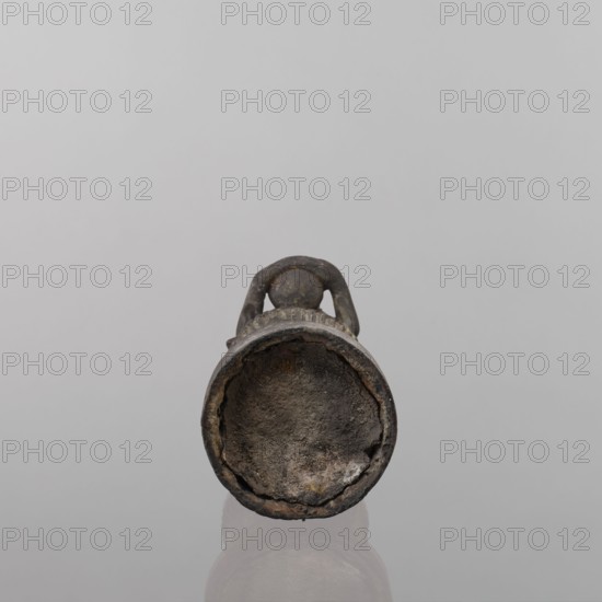 Buddha, lotus throne iconography, art of Southeast Asia, Buddha iconography, bowls, Buddhist art, 19th century, Southeast Asia, sculpture, figurine, height 54.5 cm, A small, rounded object with a hollow, circular opening faces forward, showing an uneven, textured interior rim and a rough, cratered bottom surface; a curved handle arches from the top and connects to the body, and the object rests on a reflective surface that creates a faint mirrored shape below. Colors visible include gray, dark brown, and hints of rust-colored tones.