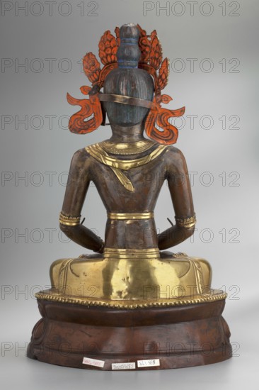 Amitayus; creator, Buddhist/Tibetan/Mongolian/Himalayan art; iconography: Buddha with ushnisha, lotus throne, vajras; 2nd half of the 18th–1st half of the 19th century; Inner Mongolia; sculpture/figurine cult object; height 37.5 cm; weight 2.12 kg, A seated statue shown from the back, with a bronze-brown body and metallic gold elements on the shoulders, waist, and seat, wearing a crown-like ornament that has bright orange-red decorative pieces and a blue-green topknot, arms resting on the lap with gold bracelets, and a rounded wooden base that is dark brown with a few lighter worn areas.
