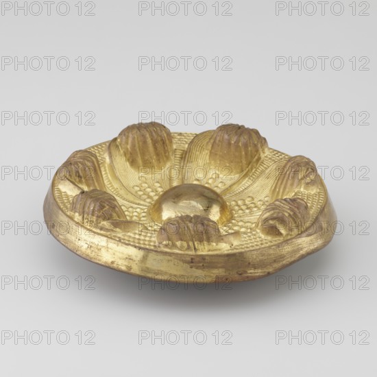 Seven-leaf rosette, craft, Tibetan, provenance unknown, rosettes, leaves ornament, decorative elements, 19th century, Tibet; Mongolia, various, height 4.3 cm, diameter 12.4 cm, A shallow round object with a metallic golden surface, appearing slightly tarnished in places, shaped like a stylized flower with a raised smooth central dome and a ring of petal-like forms around it; the petals have ridged textures and clustered bead-like details between them, and the rim shows some wear and darker spots. The visible colors are gold with areas of darker brownish-gold and small patches of darker discoloration, set against a light gray background.
