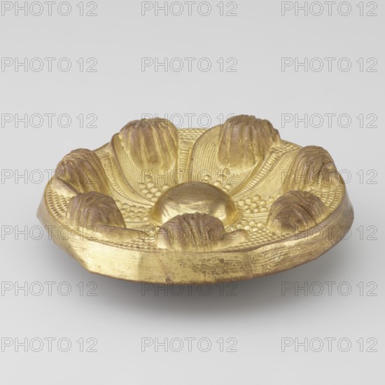 Seven-leaf rosette; maker, craft; Tibetan style; provenance, rosettes; leaves ornament; decorative elements; 19th century; Tibet; Mongolia; varia; height 4.3 cm; diameter 12.4 cm, A shallow decorative dish with a metallic gold surface placed on a light gray background, featuring a raised central dome and a surrounding ring of rounded petal-like forms with textured ridges and small bead-like details, showing areas where the gold appears slightly darker or worn to a brownish tone.