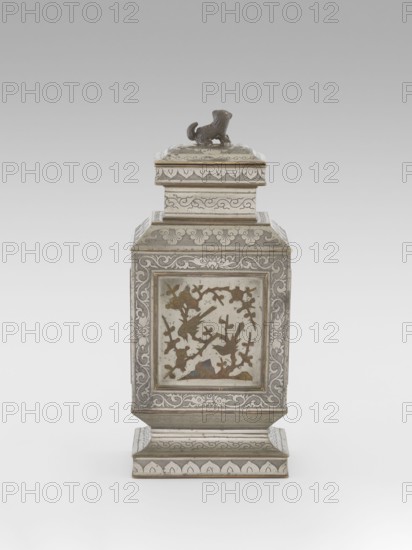 Teapot with a lid, tea, plums, images of birds, Chinese art, plant ornament, Chinese culture, restitution provenance, lions iconography, birds and flowers, huaniao style, fo iconography, plant twig, Qing style, clouds, Qing 1644–1911. Teapot with a profiled foot and neck, with a rectangular lid topped with a plastic figurine of a lion. Decorated with panels filled with a motif of a blossoming plum tree and birds, bordered with plant twigs the motif in the panels is engraved and set with metal. Foot, neck and cap decorated with plant ornament powdered background. 19th century, China, vessel; height 27.3 cm, width 11.5 cm, depth 8.3 cm., A rectangular metal container with a stepped base and a square lid topped by a small sculpted animal figure, all in shades of silver and gray with areas of darker patina and hints of brownish-gold tones; the sides display framed panels containing decorative scenes of birds and branches in muted brown and gold against a light silvery background, while the...