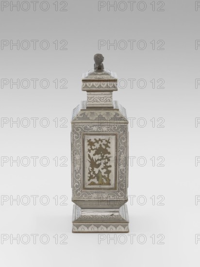 Teapot with a lid, tea, plums, images of birds, Chinese art, plant ornament, Chinese culture, lions iconography, birds and flowers, huaniao style, fo iconography, plant twig, Qing style, clouds, Qing 1644–1911. Teapot with a profiled foot and neck, with a rectangular lid topped with a plastic figurine of a lion. Decorated with panels filled with a motif of a blossoming plum tree and birds, bordered with plant twigs the motif in the panels is engraved and set with metal. Foot, neck and cap decorated with plant ornament powdered background. 19th century, China, vessel; height 27.3 cm, width 11.5 cm, depth 8.3 cm., A tall rectangular ornate container with a stepped base and a tiered lid topped by a small sculpted figure, rendered in metallic silver tones with areas of muted gold and pale green; the sides show decorative panels with floral and foliate motifs and scrolling patterns in silver and gold, and the lid and base carry complementary engraved ornamentation in silver; the overall col...