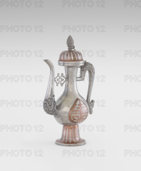 Wine jug, Chinese, plastic decorations of lotuses and longevity shou and dragons, Qing 1644–1911, early 20th century, China; vessel; height 26.8 cm, width 17.5 cm, A metal ewer with a bulbous body, a tall fluted foot, a long curved spout, and a sinuous handle; the surface shows a combination of silver-gray metal and reddish-brown accents, with decorative raised patterns on the spout end and handle, a domed lid topped by a pointed finial with carved details, and a teardrop-shaped panel on the body featuring a geometric motif in reddish-brown.