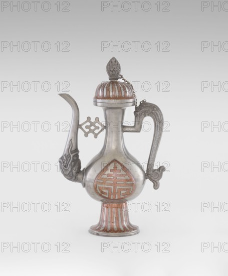 Wine jug, Chinese, plastic decorations of lotuses and longevity shou and dragons, Qing 1644–1911, early 20th century, China; vessel; height 26.8 cm, width 17.5 cm, An ornate metal vessel with a bulbous body, a long curved spout, and a tall handle is shown against a neutral background; the vessel has a domed lid topped with a finial and a short chain connecting lid to handle, decorative raised patterns on the spout and handle, a patterned recessed design on the body, and a flared foot with vertical ridges; visible colors include silver and copper tones, along with shades of gray.