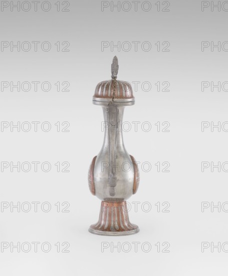 Wine jug, Chinese, plastic decorations of lotuses, longevity shou character, and dragons; Qing dynasty 1644–1911, early 20th century; ceramic vessel, height 26.8 cm, width 17.5 cm., A tall, narrow metallic vessel with a rounded base and slender neck topped by a domed lid and a decorative finial, showing a smooth silver surface with copper-colored accents on the lid, sides, and flared foot; a short decorative chain hangs from the lid down the neck, and the base and lid display fluted copper-colored panels contrasting with the silver body.