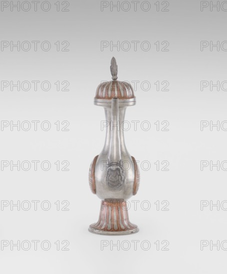 Wine jug, Chinese, plastic decorations, lotus and lotuses, longevity shou, dragons, Qing 1644–1911, early 20th century, China, vessel; height 26.8 cm, width 17.5 cm, A single ornate vessel stands alone against a neutral light gray background, with a bulbous central body tapering into a long narrow neck and topped by a domed lid with a pointed finial; the object shows a combination of silvery metallic and warm brown tones, with the brown appearing in ridged, petal-like motifs on the lid, on rounded side panels, and around the flared base, while the metallic surface is smooth and reflective with sculpted raised decorative elements on the front and sides.