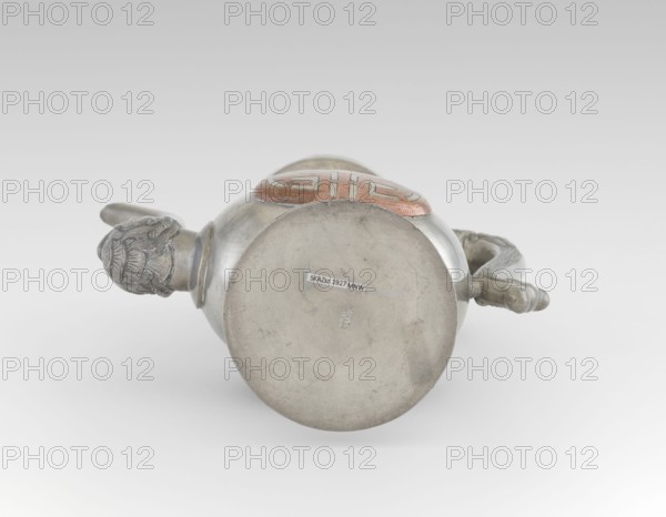 Wine jug, Chinese, plastic decorations of lotus and lotuses, longevity shou character, dragons, Qing dynasty 1644–1911, early 20th century, China, vessel; height 26.8 cm, width 17.5 cm, A metal vessel lying on its side with a rounded base and a handle, showing a decorative knob shaped like a head at one end and a curved handle with a textured grip at the other; the vessel has a circular medallion on top with a raised pattern and visible wear; colors visible include silver-gray metal, a copper-toned medallion, and subtle variations of gray in the background and shadows.