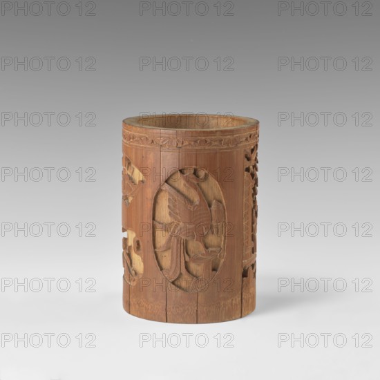 Brush vessel, Chinese, Qing dynasty 1644–1911, early 20th century. Porcelain container with reserves of bas-relief decoration showing figural scenes in a landscape and images of birds; various shapes. Height 16.4 cm; diameter 11.9 cm., A cylindrical wooden container with carved decorative panels sits against a smooth neutral background; the container shows a natural brown wood color with variations in tone, and carved motifs include a bird in an oval panel surrounded by floral and geometric patterns, with carved relief and openwork on the sides and a carved band near the rim.