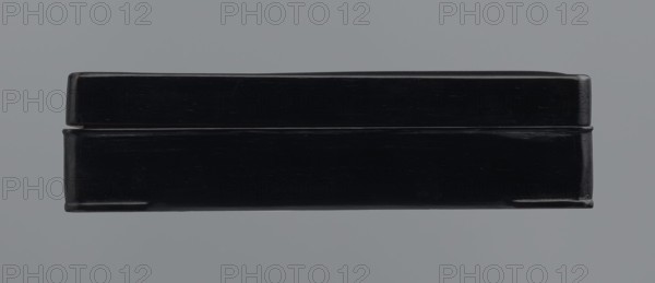 Ink stone box, ink; container; Chinese and Japanese art/culture; unknown provenance; 19th–20th century, Japan, China ; container; height 4.0 cm, width 16.0 cm, depth 22.5 cm, A rectangular hard case with a glossy black finish sits centered against a flat gray background, showing a lid slightly overhanging the base and subtle scuff marks and scratches on its surface; the case has rounded corners and a thin seam where the lid meets the base, with highlights reflecting off the black sheen and small areas of darker shadow along the edges.