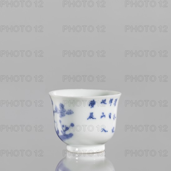 Bowl, Japanese art, Japanese culture, ceramics, blue-and-white porcelain, fishermen, figures in a landscape, 18th century, Japan, vessel, height 3.8 cm, width 5.0 cm, A small white porcelain cup with a flared rim and a narrow foot, decorated with blue painted motifs including floral elements and a group of vertical shapes, set against a plain light gray background and reflected faintly on the surface beneath; visible colors include white, blue, and gray.
