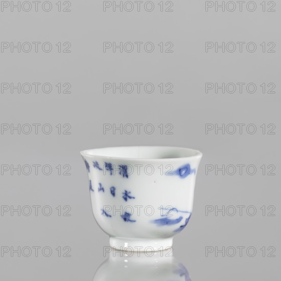 Bowl, Japanese art, Japanese culture, ceramics, blue-and-white porcelain, fishermen, figures in a landscape, 18th century, Japan, vessel, height 3.8 cm, width 5.0 cm, A small white porcelain cup with blue painted markings and brushstrokes sits on a reflective surface against a soft gray background; the cup has a slightly flared rim, a rounded body tapering to a short foot, and shows several blue decorative spots and flowing brush lines on its exterior.