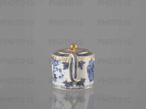 Teapot with a lid, maker, Chinese, Qing dynasty 19th century, 1644–1912; blue-and-white porcelain teapot, part of a 22-piece tea and coffee service includes teapot, 6 cups, 6 bowls, 6 saucers, a bowl, a lid and a plate; landscape motifs; vessel; height 11 cm, width 21.9 cm, diameter 11.6 cm., A small cylindrical porcelain container with a lid sits on a reflective surface; it is predominantly white with detailed blue painted scenes and floral motifs, and features gold accents on the lid, rim, and a rounded gold finial on top. The container has an ornate handle with blue and gold trim and decorative blue floral reliefs around its sides. The background and surface are a uniform gray, and the container's reflection is visible beneath it.