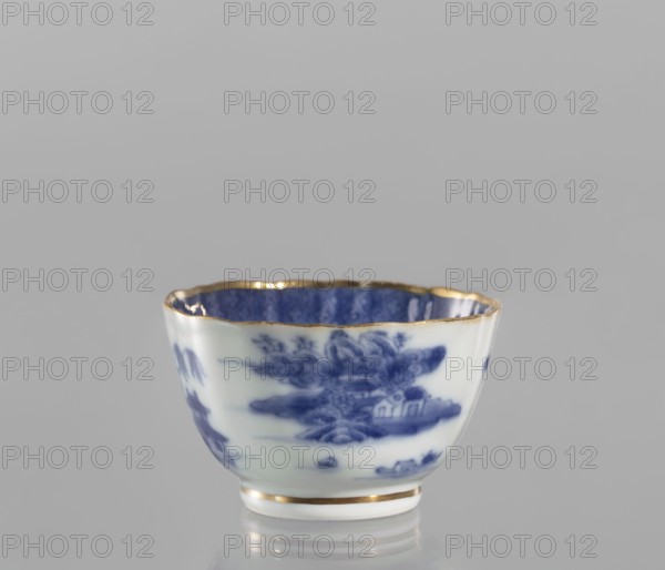 Bowl, ceramics, blue-and-white porcelain, landscape motifs, Qing style, 19th century Qing dynasty, 1644–1912, China; part of a 22-piece tea and coffee set teapot, 6 cups, 6 saucers, a bowl, a cover, and a plate; vessel, height 5 cm, diameter 8 cm., A small porcelain cup shown against a neutral gray background, with a scalloped rim edged in gold and a thin gold band near the base; the exterior is white with blue painted landscape-like patterns and the interior appears deep blue with gold trim; visible colors include white, blue, gold, and gray.
