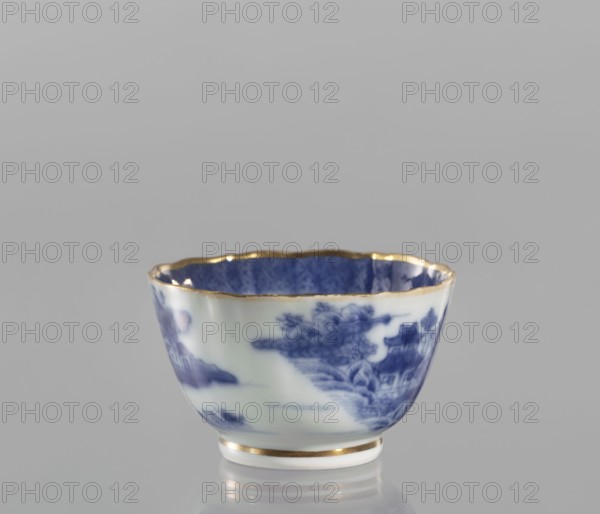 Bowl, ceramics, blue-and-white porcelain, landscape motifs, Qing dynasty style, 19th century Qing dynasty, 1644–1912, China; part of a 22-piece tea and coffee set including a teapot, 6 cups, 6 saucers, a cover, and a plate; vessel; height 5 cm, diameter 8 cm., A small porcelain bowl with a scalloped rim highlighted in gold sits against a plain gray background, showing a blue and white painted landscape scene on its exterior and a deep blue patterned interior; the bowl has a white base ring also trimmed in gold and displays shades of blue, white, gray, and metallic gold.