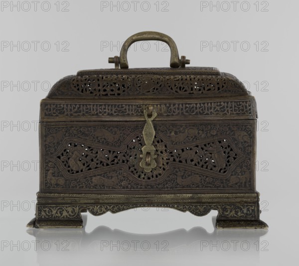 Box; rectangular box on four feet with lid and a handle on top. 19th century; Iran Qajar dynasty, Persian. Materials/technique: decorated box. Decoration: animals, hares, fantasy figures, hunting scenes, archers, figurative motifs, inscriptions, handles. Height 19.9 cm; width 15.6 cm; depth 13.8 cm., ., An ornate metal box with a handle on top, shown against a plain light gray background. The box has a rectangular base with a curved top and sits on decorative feet; its surface is covered in intricate openwork and engraved patterns. A decorative metal latch hangs from the front center, and there are pierced panels with floral and geometric motifs. The colors visible are dark brown, bronze, and muted gold, with subtle variations and a slightly aged patina.