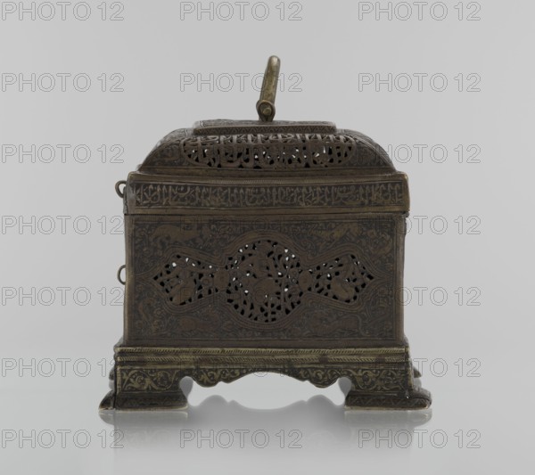 Box; Persian Iran, Qajar dynasty 1785–1925, 19th century. Rectangular box on four feet with lid and handle on top; decorated with figurative motifs including animals, hares, fantasy figures, hunting scenes, and archers; inscriptions. Materials and techniques not specified. Dimensions: height 19.9 cm, width 15.6 cm, depth 13.8 cm., An ornate rectangular metal box with a hinged domed lid and a central handle, shown from the front on a reflective surface; the box is dark brass to bronze in color with areas of darker patina and subtle greenish highlights, and it features pierced decorative patterns on the front panel and lid, raised floral and foliate engravings around the pierced areas, ornate border bands, ring attachments at the sides, and a shaped base with carved feet and decorative motifs.
