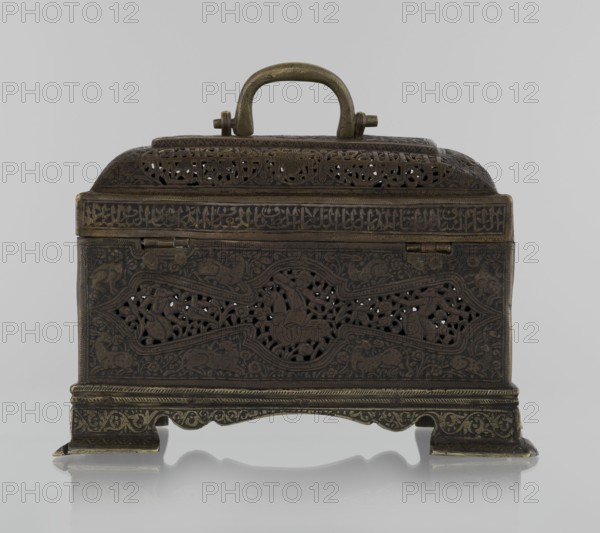 Box; Persian Qajar dynasty, 19th century. Rectangular box on four feet with a lid and a handle on top. Decorated with animal and figurative motifs hares, fantasy figures, hunting scenes, archers, inscriptions; materials/technique imply Islamic art. Height 19.9 cm, width 15.6 cm, depth 13.8 cm., An ornate metal box with a handle on top, shown against a pale gray background, featuring intricate openwork patterns and decorative motifs across its surfaces; the box rests on a decorative base with curved feet and displays a patina of dark brown and antique brass tones, with visible details in darker and lighter shades of brown and muted gold.