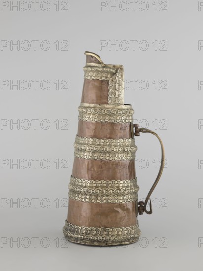 Tea pot, craft vessel, Tibetan teapot/kettle/tea vessel, jug tapering towards the top, silver fittings, brass handle, 19th century, Tibet, height 35.0 cm, width 19.0 cm, diameter 15.0 cm, The image shows a tall, conical metal vessel with a curved handle on one side and a spout at the top; the body of the vessel is a warm brownish-copper color with several decorative horizontal bands of a pale silvery color encircling it, and the handle appears brass-colored with a slightly darker hinge attachment; the background is a smooth, light gray.