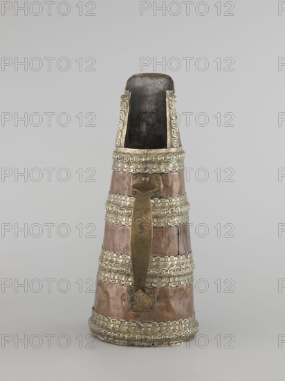 Tea pot, 19th century, Tibet. Teapot/kettle; vessel tapering towards the top with brass handle and silver fittings. Height 35.0 cm; width 19.0 cm; diameter 15.0 cm. Tibetan craft, tea vessel., An upright conical vessel with a narrow open top and a wider base, featuring a metallic brown body accented by several horizontal decorative bands of silvery metal; a long vertical handle of darker brass-like color with engraved patterns runs down the front and is attached near the top and bottom; the interior visible at the top is dark, and the silvery bands and rim display embossed interlocking designs; the overall colors visible are brown, silvery gray, dark brass, and dark gray.