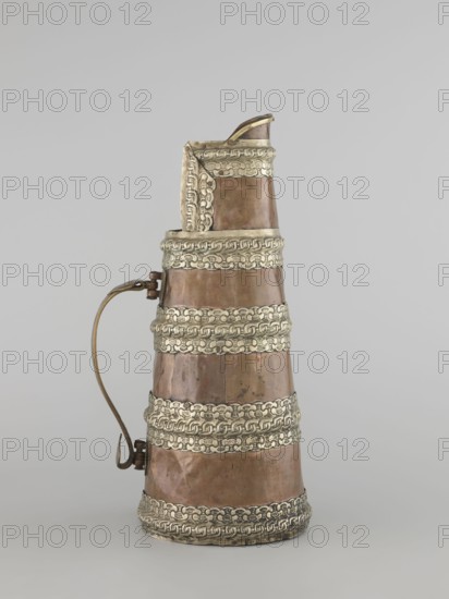 Teapot, maker, 19th century, Tibet. Teapot jug tapering towards the top with silver fittings and a brass handle; vessel for tea. Dimensions: height 35.0 cm, width 19.0 cm, diameter 15.0 cm., An upright conical vessel with a curved handle on one side, showing a metallic surface in shades of brown and bronze with decorative horizontal bands in a lighter silvery color; the vessel tapers toward the top and has a small spout, and the silvery bands feature repeating raised patterns around the circumference against the brown body, all set against a plain light gray background.