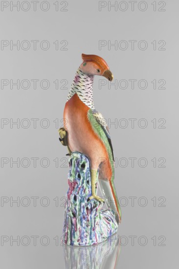 Pheasant figurine, Chinese art, Chinese culture, Qing dynasty 1644–1911, ceramics, colored porcelain, animal figurine depicting a pheasant on rocks, 19th century, China, sculpture; height 49.0 cm, width 20.0 cm, A colorful ceramic bird perched on a textured base, with an orange head and upper body, a pale patterned neck with black markings, and green and blue accents on the wings and tail; the bird has a brownish beak and yellow scaly legs and claws gripping a multicolored base that shows shades of purple, blue, green, and pink against a neutral gray background.