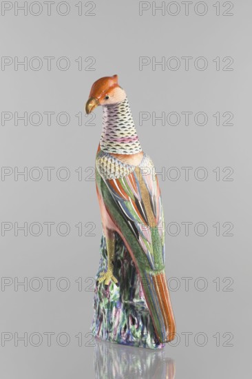 Pheasant figurine; creator, Chinese; Qing dynasty 1644–1911; 19th century; colored porcelain; sculpture of a pheasant and rocks; ceramic animal figurine bird; height 49.0 cm, width 20.0 cm., A colorful ceramic bird perched on a textured base is shown against a plain gray background, featuring an orange head with a golden beak, a neck with pale tones and black scale-like markings, and a body decorated with patterned feathers in green, blue, orange, pink, purple, white, and gold; the base displays marbled greens, purples, and whites, and the bird’s talons are yellow.