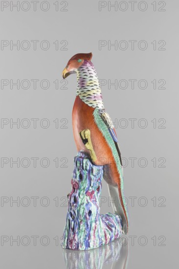 Pheasant figurine, unknown creator; Chinese art; Chinese culture; Qing dynasty 1644–1911; 19th century; ceramics, colored porcelain; sculpture of a bird pheasant on rocks; height 49.5 cm, width 19.8 cm, depth 17.0 cm; weight 3.36 kg., A painted ceramic bird perched on a sculpted base, with a reddish-brown head and body, a yellow beak, and a throat and upper neck patterned with pale green, light purple, and pale yellow scale-like markings; the bird has teal and green feather accents along its wing and tail, a blue eye area, and a yellow textured talon resting on a multicolored base that shows shades of teal, purple, blue, and pink with glossy highlights.