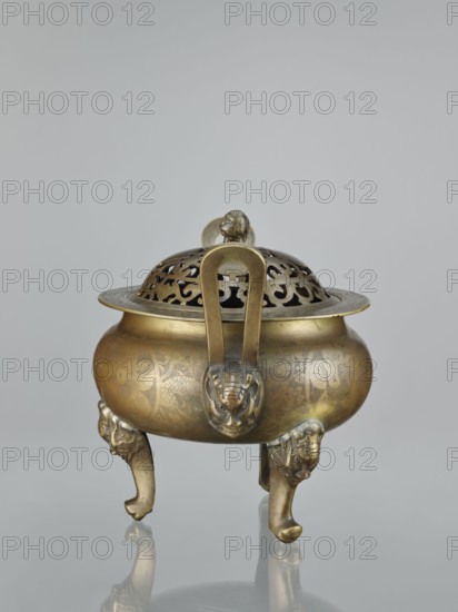 Ding-type incense burner with cover, made by, Chinese, Qing dynasty 1644–1911, 18th/19th century. Bronze vessel censer, height 27.0 cm. Sides of burner and cover decorated with engraved plant ornament including plum trees, bamboos, pine trees, and other plants; iconography includes bats, lions fo, hares/rabbits, deer, cranes; motifs referencing yin and yang. Ceremonial/ritual vessel., A brass vessel with a rounded body and a pierced domed lid sits on a reflective surface against a plain light gray background; the vessel has a warm golden-bronze color with darker patina in places and subtle engraved decorative patterns on its body, a large looped handle rising from the lid topped by a small sculpted knob, and three curved legs each shaped with sculpted animal heads and paws that share the same golden-bronze tones.