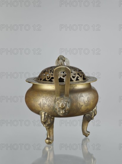 Ding-type incense burner with cover;, Chinese; Qing dynasty 1644–1911, 18th–19th century. Bronze vessel censer, height 27.0 cm. Sides of the burner and cover decorated with engraved plant ornament: plum trees, bamboos, pine trees; animal and iconographic motifs include bats, lions, fo, hares/rabbits, deer, cranes; yin and yang motifs. Ceremonial/ritual vessel., A brass censer with a rounded body and a pierced domed lid sits on a reflective surface; the metal shows golden and bronze tones with areas of darker patina and engraved floral and foliate patterns on the bowl; the lid features an openwork design and a small sculpted ring handle, and a pair of vertical handles rise from the rim to the lid attachment; the censer stands on a group of ornate legs shaped like stylized animal heads and curved feet, all in matching golden-bronze hues against a pale gray background.