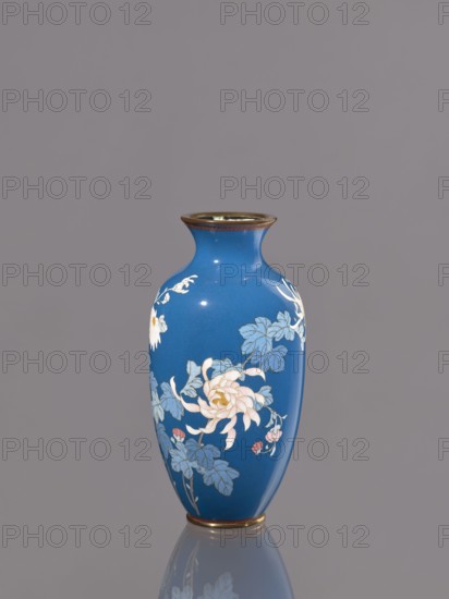 Vase with chrysanthemums, ca. 1900 Meiji 23, Japan, Nagoya; cloisonné enamel; vessel; height 18.0 cm, diameter 9.0 cm; Japanese art; Meiji 1868–1912; chrysanthemums, flowers iconography., A single blue vase with a narrow neck and flared rim stands centered against a plain gray background, decorated with floral motifs in pale pink, white, light blue, and muted green, with touches of gold at the rim and base, and a soft reflection visible beneath it.