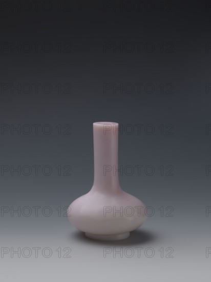 Vase, Chinese, Qing dynasty, Qianlong period 1736–1795. Flask of pale pink glass on a low ring foot with a straight long cylindrical neck. Vessel; height 13.6 cm, diameter 9.8 cm, weight 0.35 kg., A single vase with a long narrow neck and a rounded bulbous base sits centered against a smooth gradient background; the vase is a pale pink color with a glossy surface that reflects light, and the background shifts from dark gray at the top to lighter gray toward the bottom.