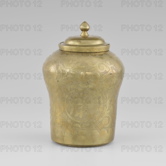 Tin with a lid, tin with the top widened, early 20th century, Korea; container; height 15.0 cm, diameter 9.8 cm; decorated with peonies; Korean art; plant ornament;, A single lidded metal container with a rounded body and slightly flared base sits against a neutral gray background; the container is golden in color with a polished sheen and features etched decorative patterns of flowers, leaves, and swirling motifs covering its surface; the lid is domed with a teardrop-shaped finial on top, also golden, and the decoration includes areas of fine stippling and engraved line work; the overall color palette is gold with subtle variations in tone where light and shadow create highlights and darker areas.