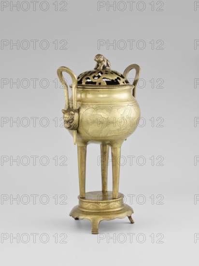 Censer with a cover, Censer with two long handles with mascarons. Decoration: two reserves—fruits and leafy twigs, animals and birds among trees. Early 20th century, Korean. Vessel censer. Height 15.0 cm; diameter 9.8 cm., A brass tripod censer with a rounded body and a pierced lid topped by a small animal figure, flanked by two curved handles and mounted on three long tapering legs connected to a circular stepped base with short bracket feet; the body shows incised decorative motifs and a sculpted animal head where a handle meets the rim. The visible colors are brass gold and subtle darker patina tones against a light gray background.