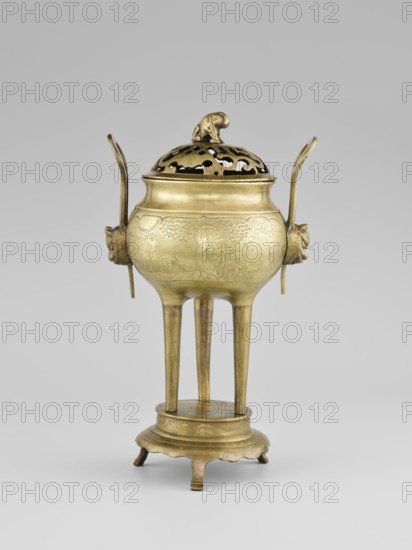 Censer with a cover, ; animals, fruits ornament, birds decorative motif, plant ornament; Korean, Korean art. Censer with two long handles with mascarons. Decoration: two reserves — fruits and leafy twigs, animals and birds among trees. Early 20th century, Korea . Vessel, censer. Height 15.0 cm, diameter 9.8 cm., A gilded metal vessel with a rounded body and a pierced domed lid topped by a small sculpted animal figure sits on a raised pedestal supported by three tall straight legs; the vessel has two upward-curving looped handles attached at opposite sides with sculpted decorative mounts, and the body shows incised decorative patterns. The overall colors visible are gold and brass tones against a neutral gray background.