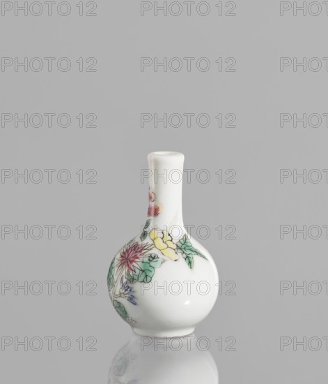 Bottle, ceramics; Chinese, 19th/20th century. Very small ovoid bottle with a long, thin, straight neck. White glaze painted with enamel paints and black contour overglaze. Unsigned. Floral decorations. Colored porcelain. Vessel. Height 5.7 cm; diameter 3.5 cm., A small rounded white porcelain vase with a narrow neck sits against a plain gray background, showing a hand-painted floral design in colors including green, pink, yellow, purple, and hints of blue; the vase's glossy surface reflects light and creates a soft reflection on the surface below.