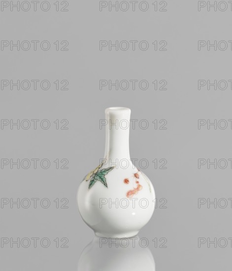 Bottle, very small ovoid bottle with a long, thin, straight neck. White glaze, painted with enamel paints and black contours overglaze; unsigned. 19th/20th century, China. Colored porcelain with floral decorations. Vessel, height 5.7 cm, diameter 3.5 cm., A small white ceramic bottle with a rounded body and a narrow neck sits against a gray background, showing a painted decoration of green leaves and small orange-red berries on its surface and a glossy reflection beneath it.