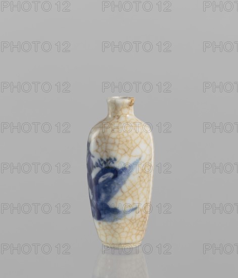 Flask-snuffbox, 19th century, China. Elongated ovoid shape with a narrow short neck; blue-and-white porcelain with bluish glaze and cracklework highlighted in brown paint; figural scenes. Vessel snuffbox, height 7.3 cm, diameter 3.5 cm., A small ceramic bottle stands upright against a plain light gray background, showing a glossy, crackled off-white surface with a network of fine golden-brown crazing lines and a blurred blue painted motif on one side; the bottle has a narrow neck with a slightly flared lip and a rounded shoulder tapering to a narrow base, and there is a subtle reflection of the bottle on the smooth surface beneath it.