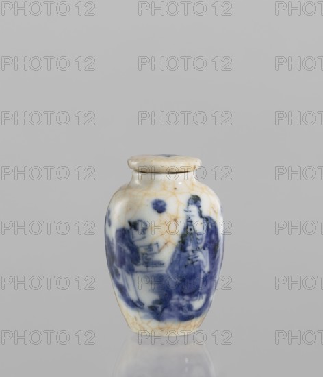 Flask - snuffbox with stopper, maker, repossession noted. Ceramics, Chinese, figural scenes, blue-and-white porcelain, cracklework decoration. The flask is short and wide with a short neck and cracklework embedded in yellow paint. The porcelain stopper is flat. The glaze is bluish, transparent, with minor impurities. Decoration is underglaze painted with cobalt. The stopper and flask are decorated with cracklework. 19th century, China; vessel; height 6 cm, diameter 4 cm., A small ceramic jar with a rounded body and a fitted lid sits against a neutral gray background; the jar is predominantly white with visible age-related hairline crack patterns in a tan color and features a painted blue scene wrapping around its body showing human figures and abstract shapes; the lid is similarly white with tan cracking and a small dark spot on top, and the base of the jar shows a subtle reflection on the surface beneath it.