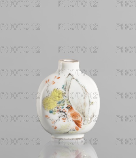 Flask — snuffbox in the shape of a pilgrim's bottle, Circular, flattened shape with a short neck. Thick porcelain body, fine-grained dough with a greyish hue, bluish glaze. Gilded rim. 19th century, China. Colored porcelain with figural scenes, images of birds, landscape motifs; moon bottle design; decorative flowers. Height 7.8 cm, width 5.1 cm., A small white ceramic vase with a rounded, flattened body and a short narrow neck sits against a plain gray background; the surface is decorated with a painted scene including a reddish-brown bird perched among branches, yellow chrysanthemum-like flowers, small orange leaves, touches of pale green and teal foliage, and a large pale beige rock-like shape, with the vase casting a soft reflection below.