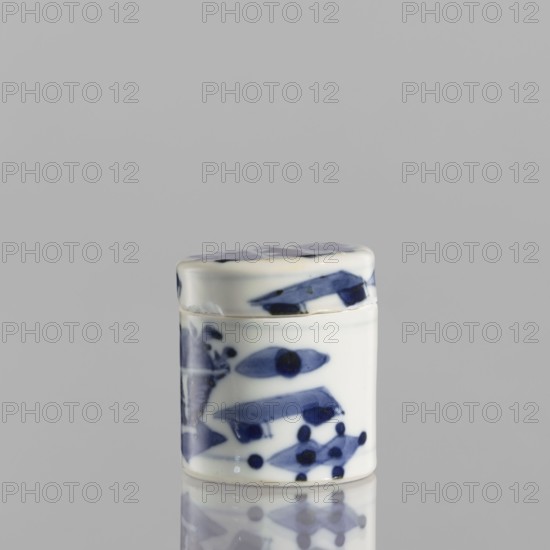 Cylindrical jar with a lid; ceramics; Chinese; blue-and-white porcelain; cylindrical vessel with attached lid; thick porcelain body, bluish-tinted paste; decoration painted underglaze with cobalt, thickly applied in places; glaze with a grayish hue; ornament: baigu one hundred antiquities; 19th century; height 5 cm, diameter 4.5 cm., A small cylindrical ceramic container with a matching lid, glossy white with blue hand-painted abstract shapes and spots, resting on a reflective surface that shows a faint mirrored image; the background is a smooth light gray.