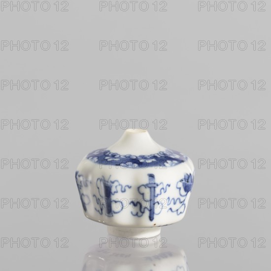 Small spice vessel, blue-and-white porcelain, 19th century China. Vessel, height 4.6 cm, diameter 5.5 cm. No stopper. Ornament: baigu hundred antiquities. Subject/materials: spices; function: spice vessel., A small ceramic object with a rounded body and a short tapered neck sits centered on a reflective surface; the object is white with blue painted decorative motifs around its body and near the top, featuring floral and abstract shapes in varying shades of blue, and the surface shows smooth glossy highlights and subtle shadows against a pale gray background.
